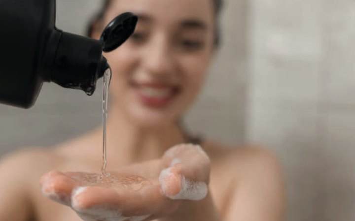 Produto de higiene capilar sendo dosado na mão antes da lavagem.