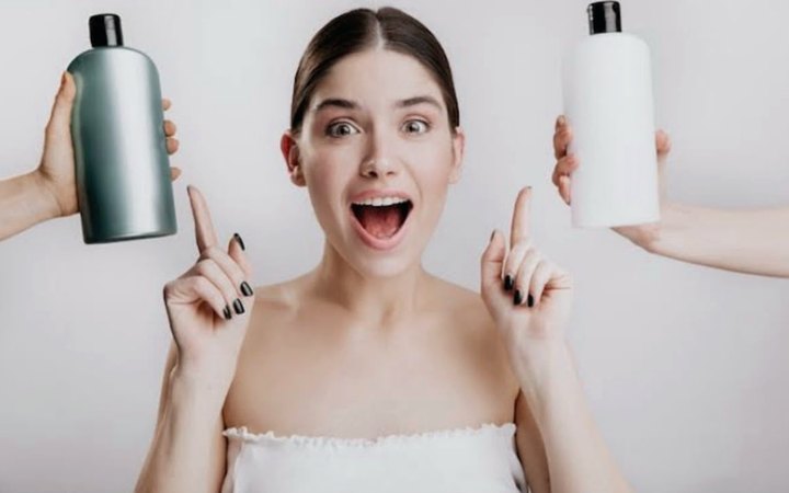 Mulher em dúvida entre dois frascos de shampoo.